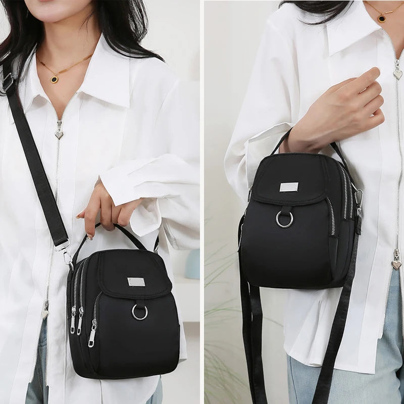 Une femme portant une chemise blanche tient un sac bandoulière floral noir.