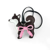 Colgante de perro Shiba Inu marrón oscuro y blanco con un lazo de cuero trenzado rosa en una correa negra.