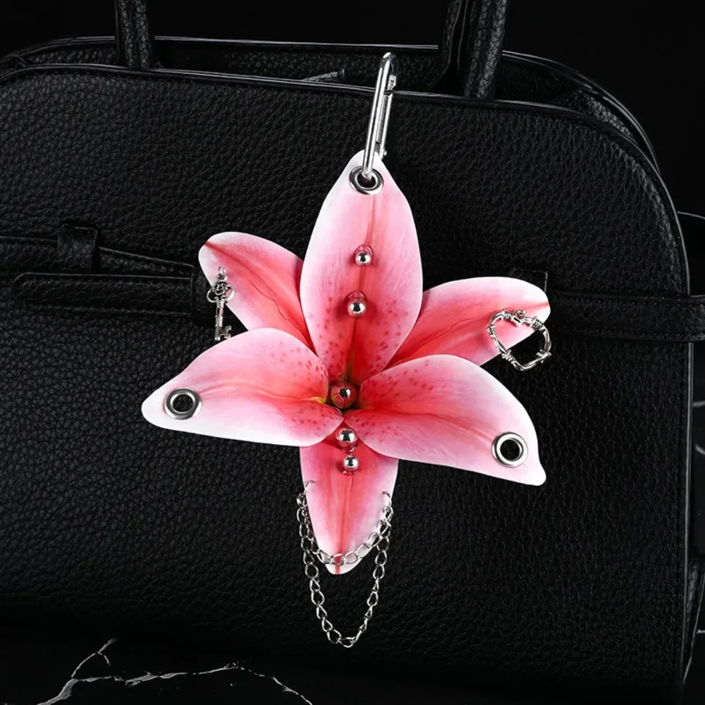 A pink orchid flower keychain attached to a black leather handbag.