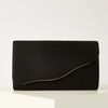 A black velvet evening clutch with a subtle gold trim resting on a white surface.