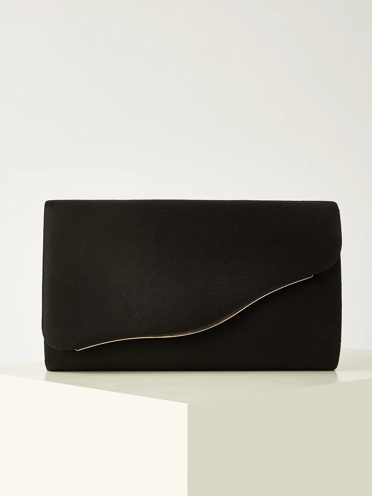 A black velvet evening clutch with a subtle gold trim resting on a white surface.