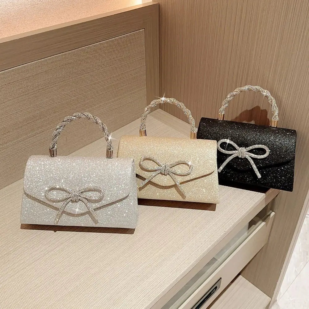 Tres bolsos de mano tipo lazo brillante para la noche en plata, beige y negro, exhibidos sobre una superficie clara.