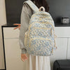 A light blue floral quilted backpack set worn by a person against a white cabinet.