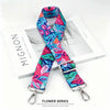 A vibrant floral patterned fabric strap in blue and pink is displayed next to a white box.