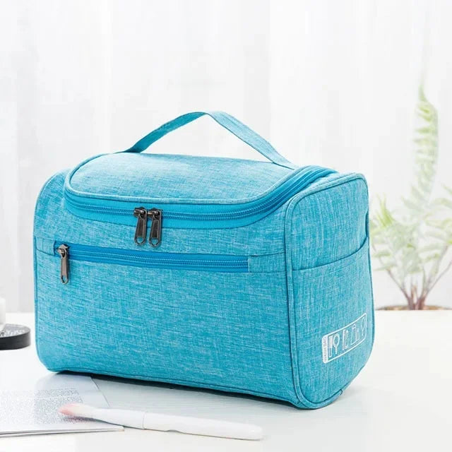 A teal portable toiletry bag with a zipper and handle is shown on a white surface.