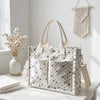 Sac fourre-tout en velours côtelé beige à motif blanc et noir, exposé sur une surface en bois à côté de fleurs séchées.