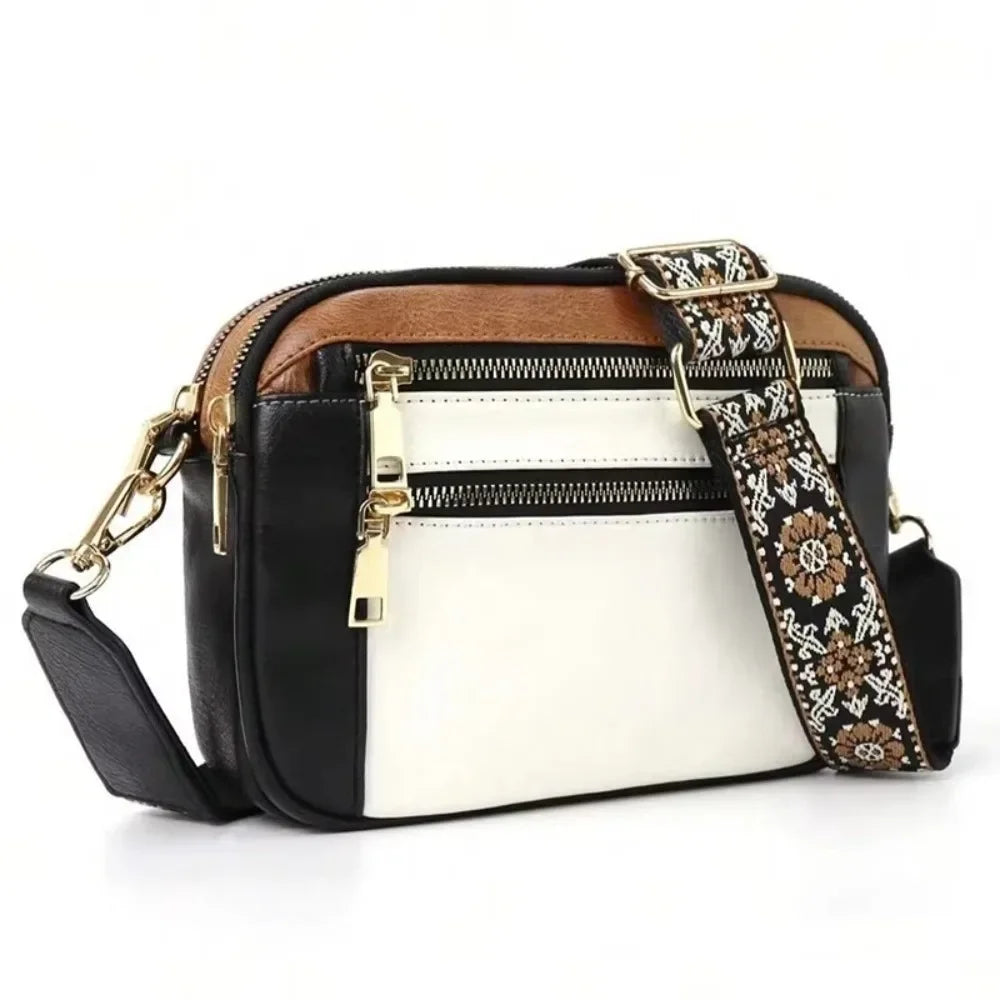 A black and white PU leather crossbody bag with brown trim and gold hardware.