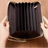 A close-up of a tan PU leather zipper clutch wallet being held and shown open, displaying various cards and items.