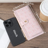 A pink folding multi-card wallet is shown next to a black smartphone and a cup on a wooden surface.