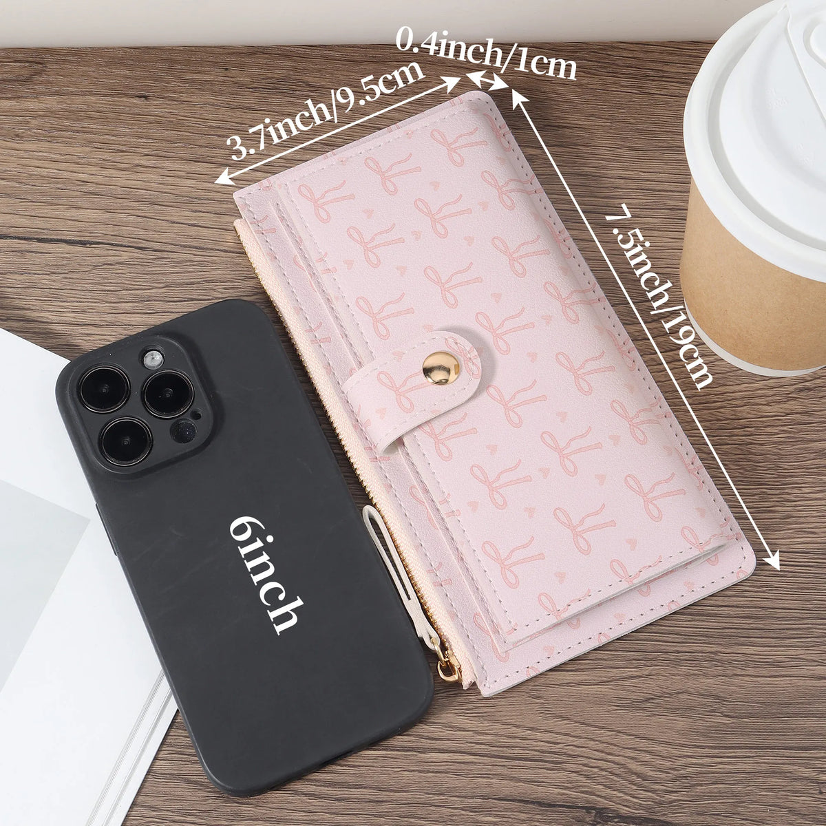 A pink folding multi-card wallet is shown next to a black smartphone and a cup on a wooden surface.