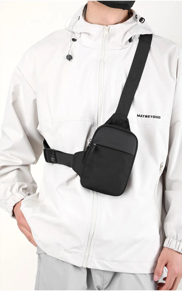 Un hombre vistiendo una chaqueta impermeable blanca con un bolso cruzado negro sujeto a su camisa.