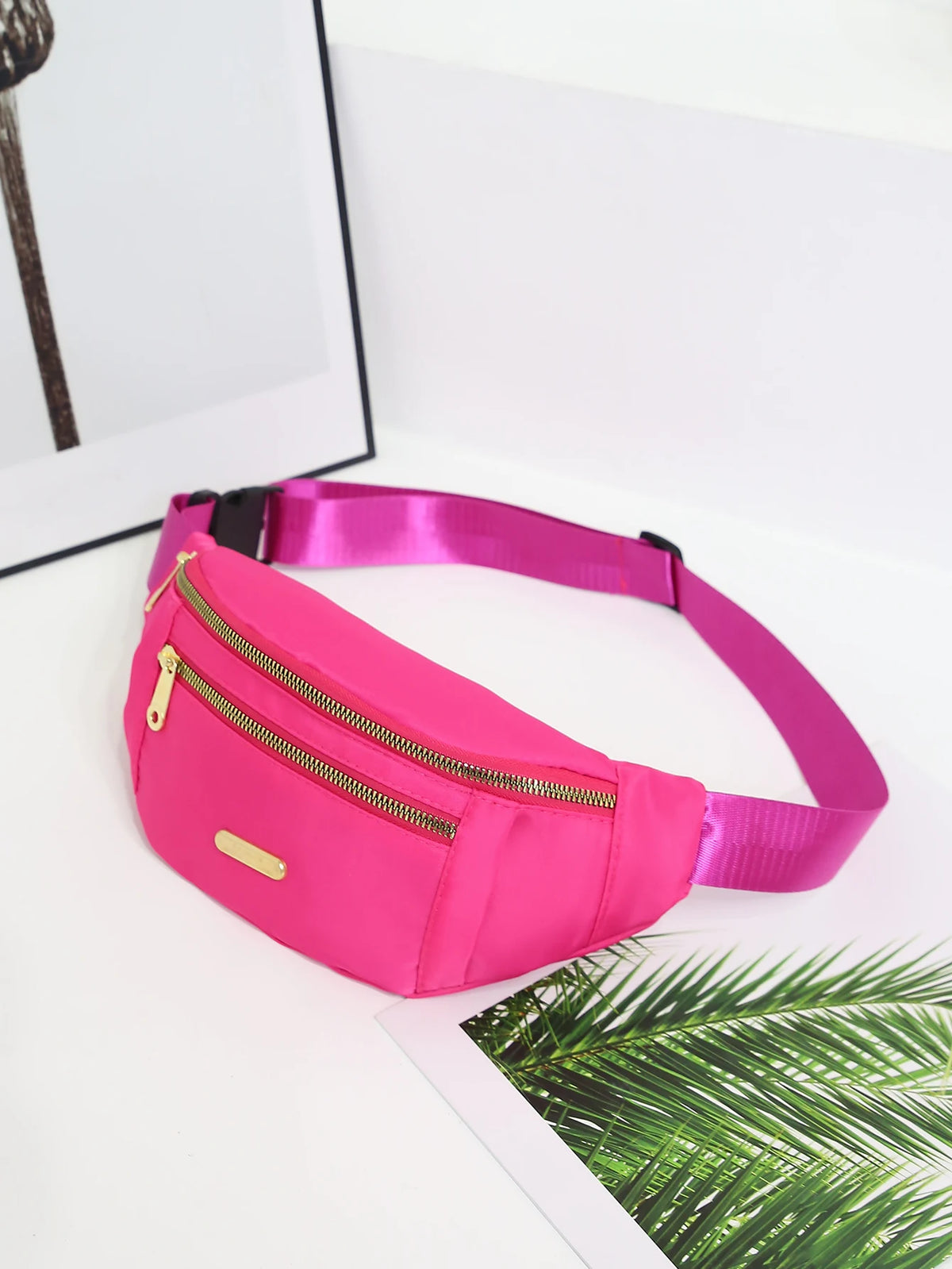 A bright pink multi-layer sports waist bag with a gold zipper is displayed on a white surface.