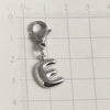 Silver stainless steel alphabet letter charm with a lobster clasp shown against a ruler.