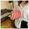 A woman wearing a white shirt holds a red and white striped crochet handbag.