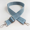 A light blue woven strap with an arrow jacquard pattern, shown crossed on a white background.