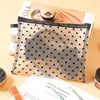 A clear mesh cosmetic storage pouch with a black and white heart pattern is shown next to a magazine.