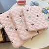 A stack of pink quilted slim laptop sleeves for MacBook and tablet placed on a white table.