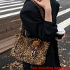 A person holds a leopard print casual tote bag in black and black clothing on an asphalt surface.