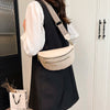 A woman is holding a beige PU leather crossbody bag with a patterned strap and a black vest.