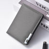 A gray slim faux leather business card wallet resting on a white surface next to a book.