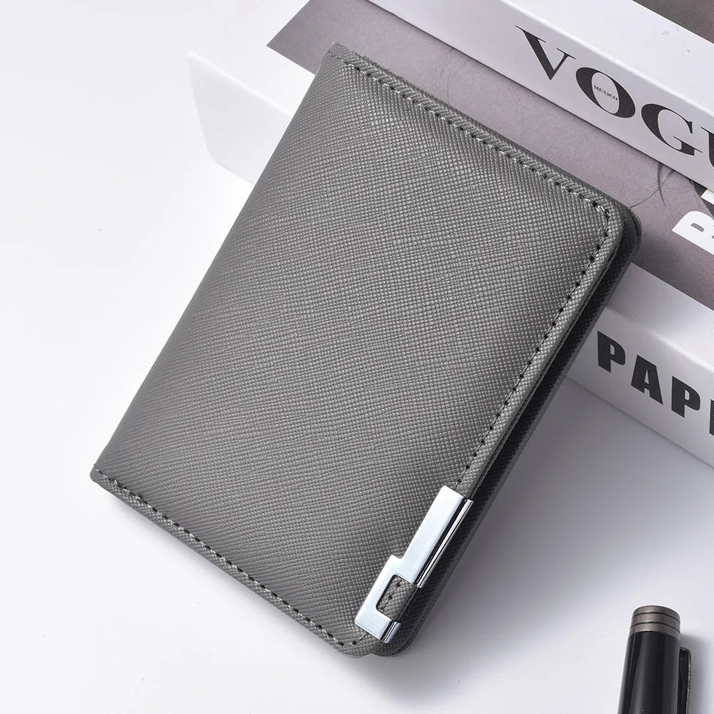 A gray slim faux leather business card wallet resting on a white surface next to a book.