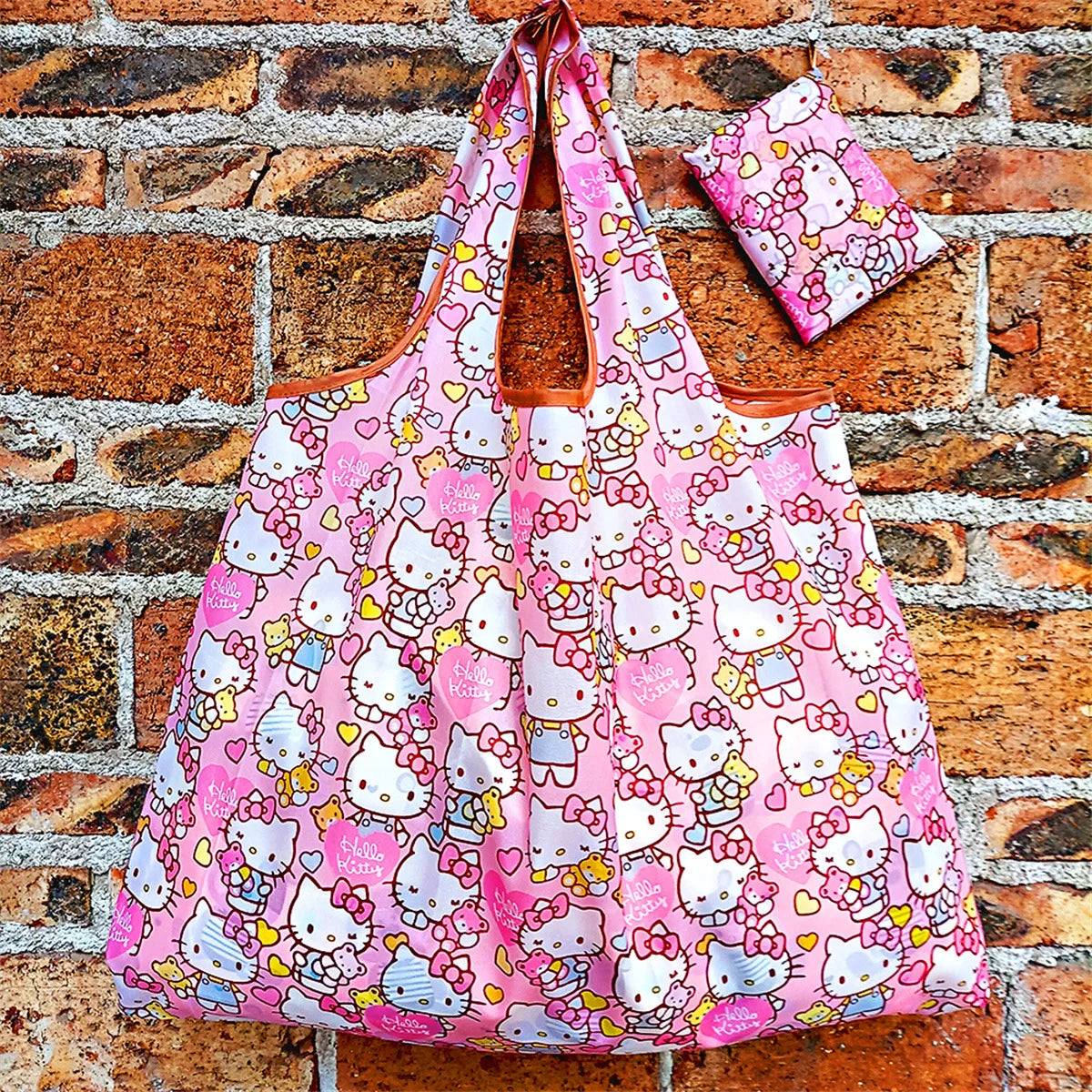 A pink and white patterned reusable shopping bag hanging against a brick wall.
