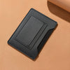 Portefeuille de voyage noir et fin, conçu pour contenir un passeport et des documents, montré sur une surface beige.