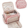 A pink quilted multi-compartment travel organizer bag with a hinged lid and an open front section.