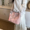 Bolso de seda jacquard rosa retro con bordado floral junto a un vestido de encaje blanco.