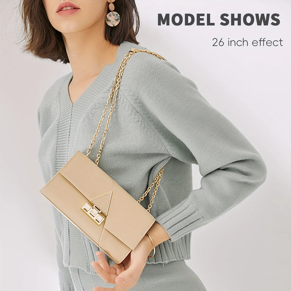 Una modelo muestra un suéter gris claro sosteniendo un bolso de cuero beige con correa de cadena dorada.