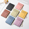 Eine Kollektion von fünf schlanken Kartenwallets in verschiedenen Pastellfarben wie rosa, gelb, grün und blau, präsentiert au