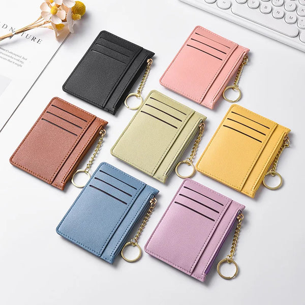 A collection of five slim card wallets in various pastel shades including pink, yellow, green, and blue, displayed on a white
