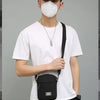 A man wearing a white t-shirt and face mask carries a black nylon crossbody bag.