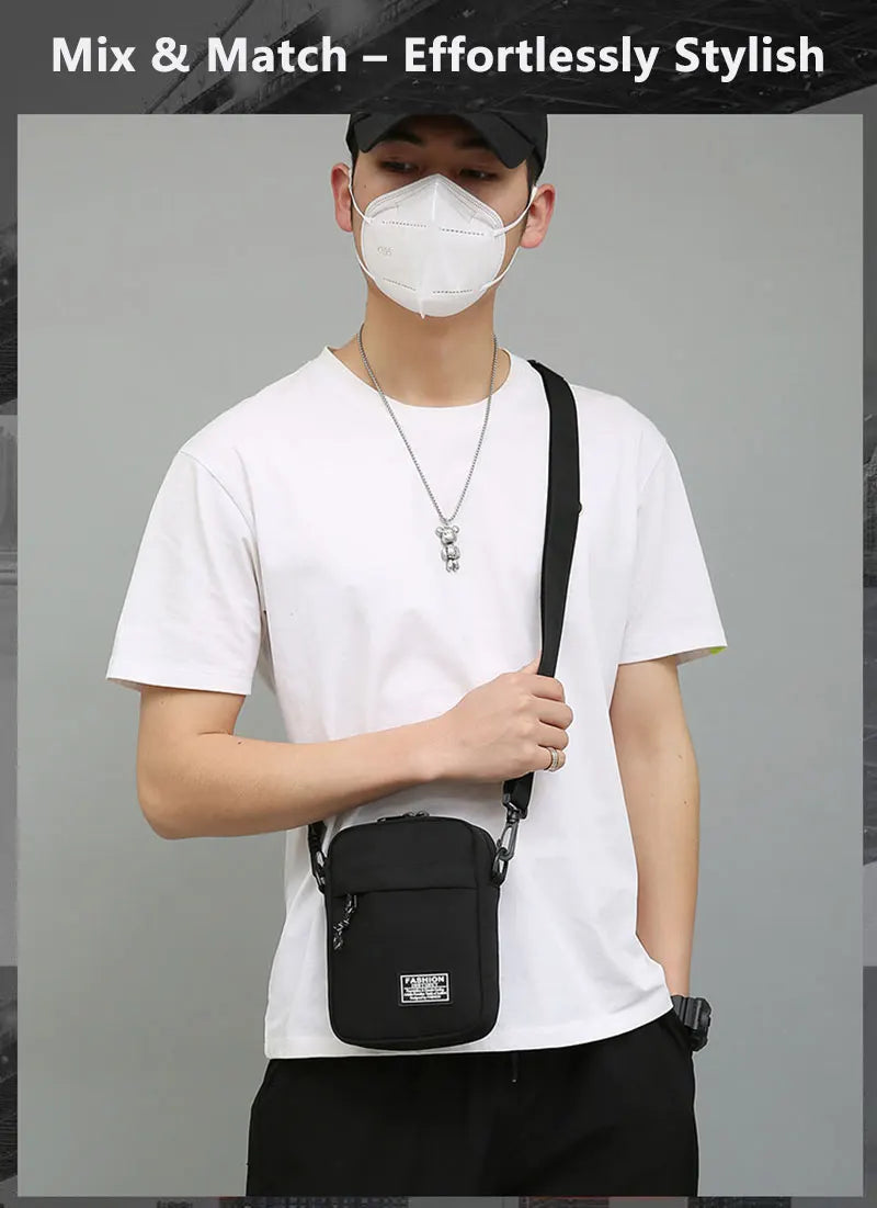A man wearing a white t-shirt and face mask carries a black nylon crossbody bag.