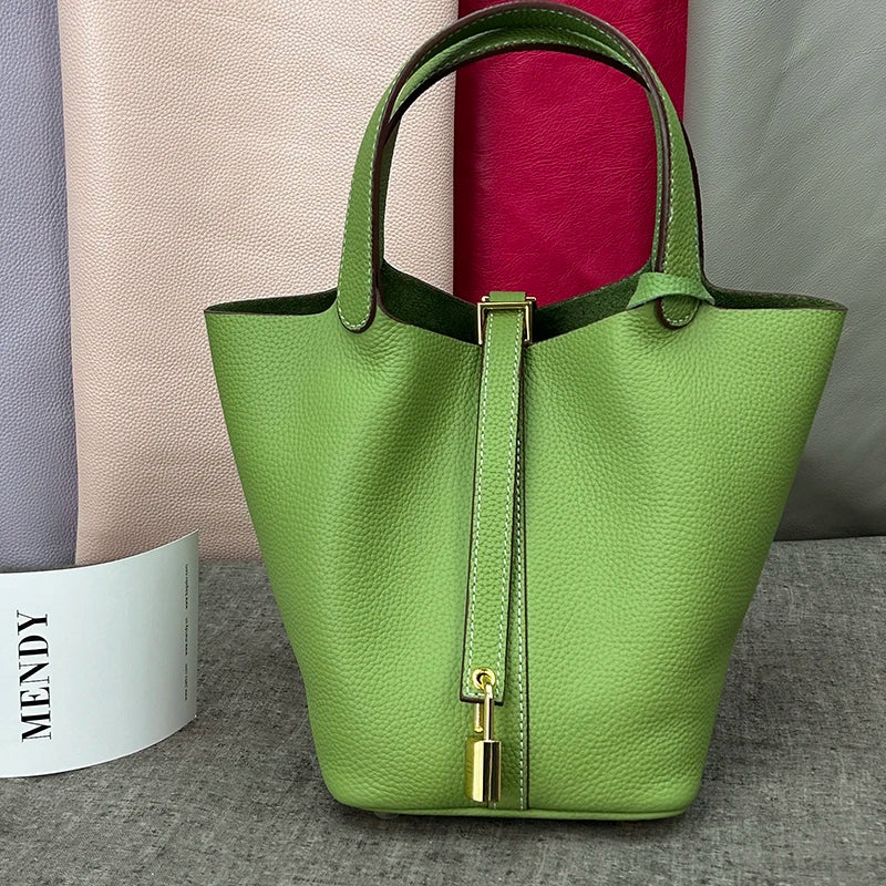 A lime green genuine leather bucket bag with a gold-toned clasp displayed on a gray surface.
