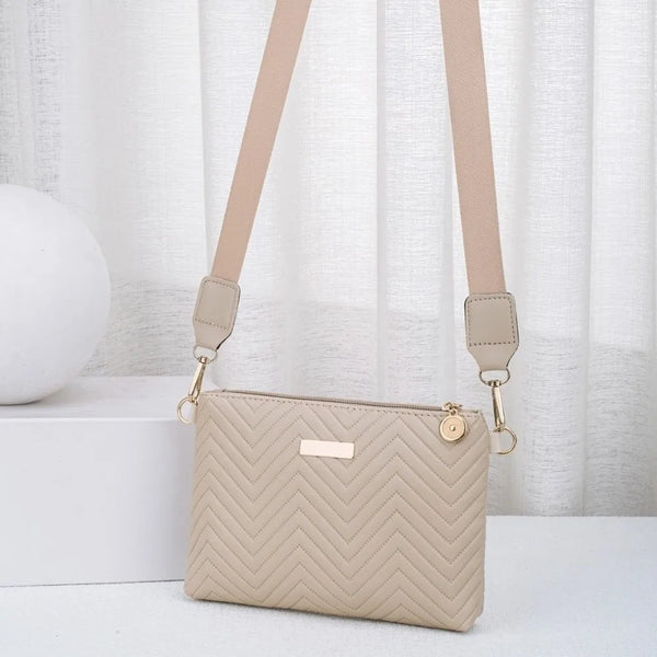 Bolso cruz acolchado beige con correa de color caqui, mostrado contra un fondo blanco.