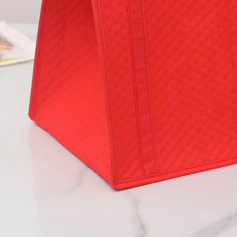 A bright red insulated tote bag with a quilted texture is shown on a white marble surface.