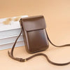 A brown vintage PU leather crossbody bag with an adjustable strap resting on a stack of white papers.