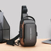 A dark brown men's oxford sling chest bag with a padded strap and a dedicated phone pocket resting on a wooden surface.