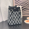 A black and white geometric pattern knitted bucket bag with gold hardware resting on a dark surface.