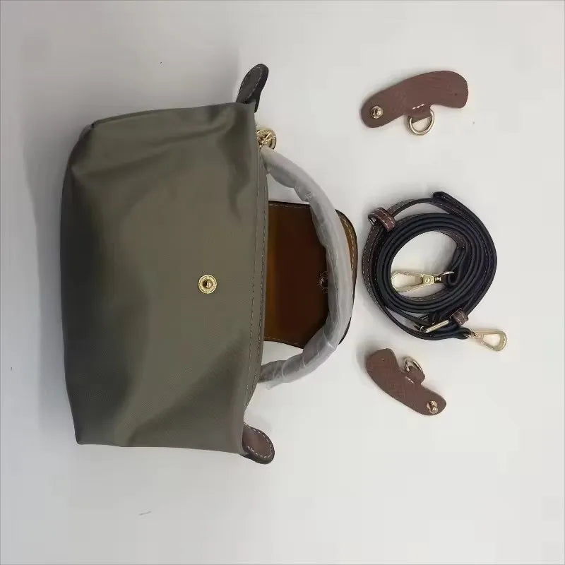 A olive green waterproof nylon crossbody bag with a brown leather interior and detachable strap components.