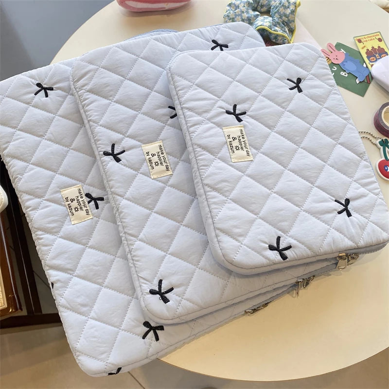 A stack of quilted white slim laptop sleeves for MacBook and tablet