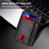 A black carbon fiber slim wallet with a red accent, shown next to a laptop keyboard.