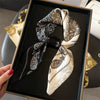 Elegant paisley silk hair scarf and headband in black and cream patterns displayed in a gold box.