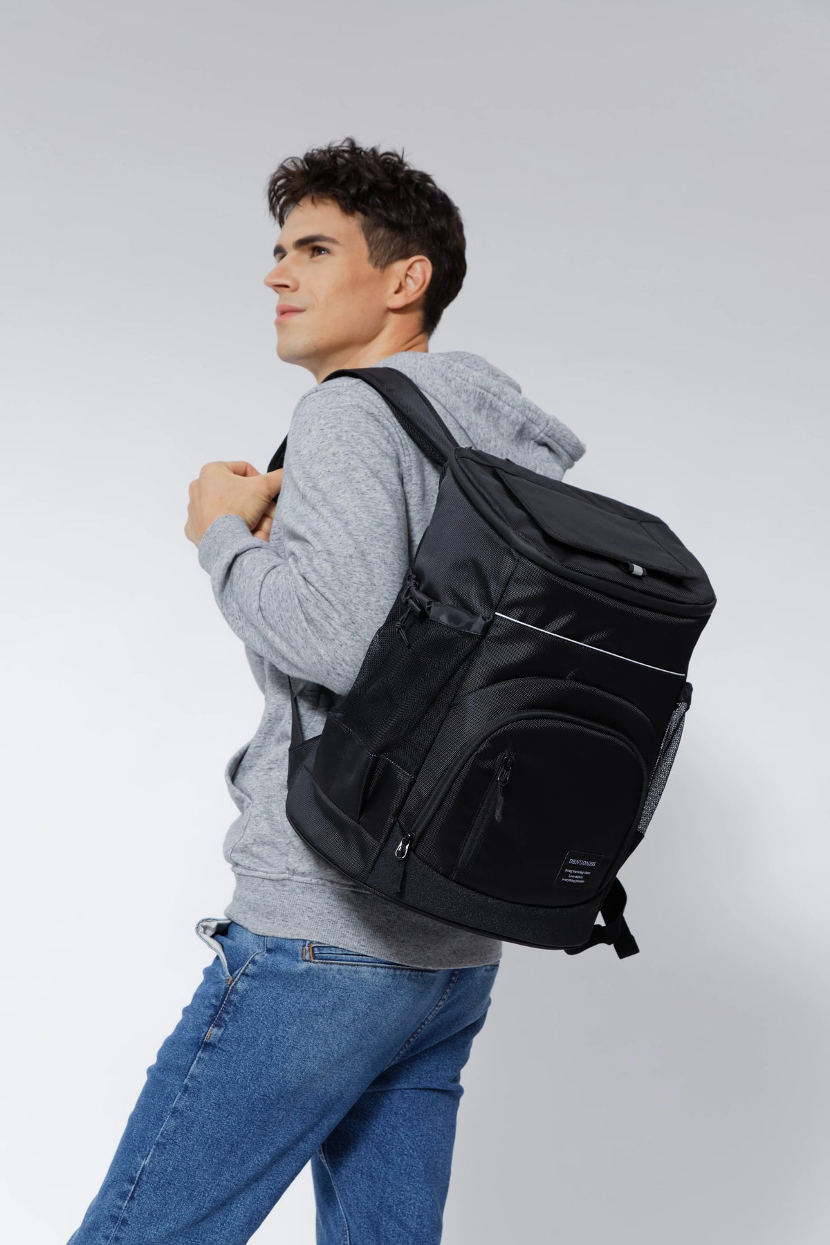 A man wearing a grey sweatshirt is holding an insulated thermal cooler backpack.