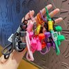 A hand holds a collection of colorful fitness keychains featuring dumbbell and kettlebell charms.