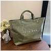 A green transparent waterproof PVC tote bag is displayed on a wooden surface next to some yellow flowers.