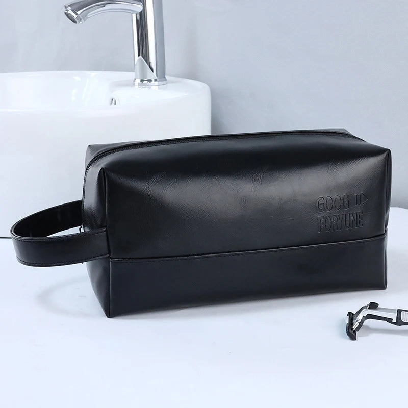 A black portable PU leather cosmetic organizer bag resting on a white surface next to a sink.