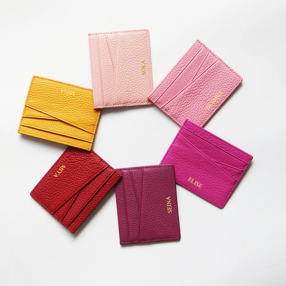 Une collection de porte-cartes en cuir véritable rose et magenta disposés en cercle.