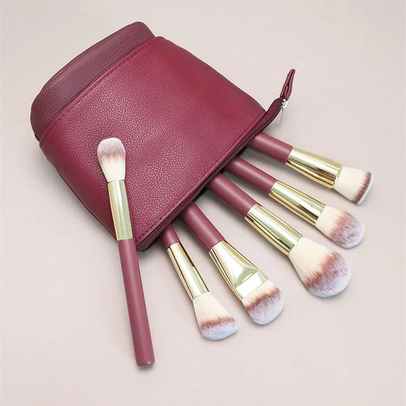 A maroon makeup brush storage case with several makeup brushes inside.